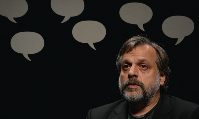 Slavoj Žižek hablando frente a un fondo oscuro, con burbujas de pensamiento que sugieren contemplación filosófica.